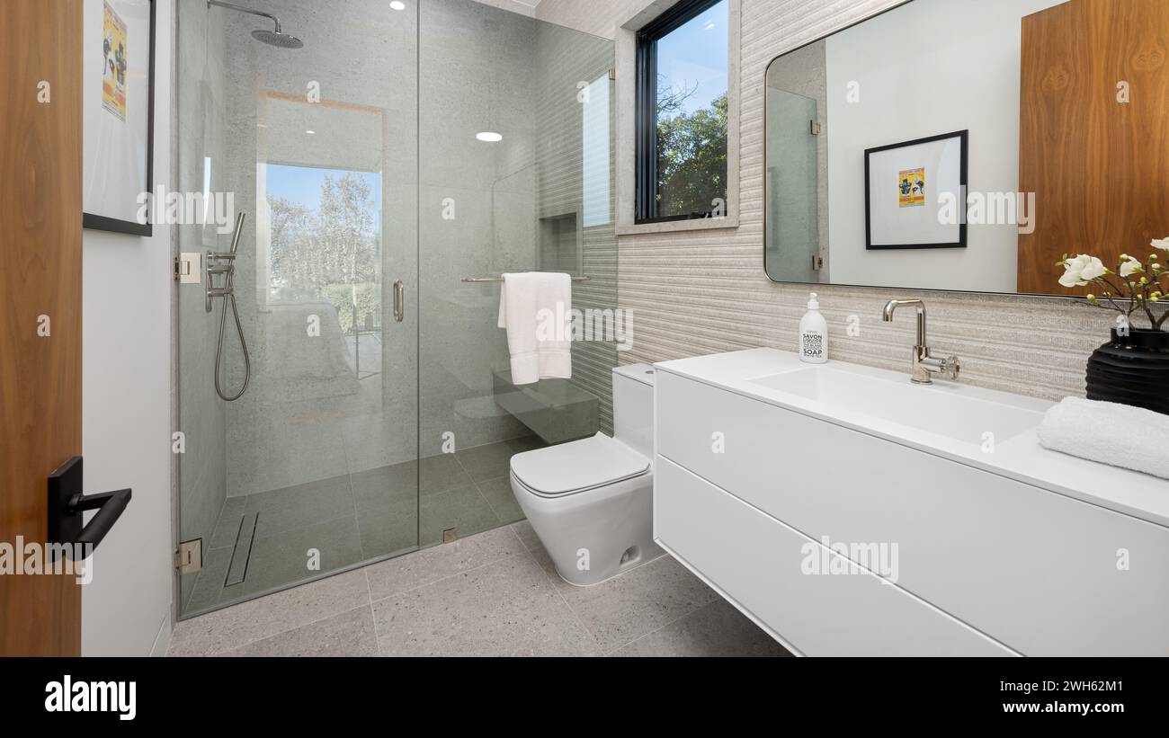 Une salle de bains moderne avec une douche à l'italienne et une coiffeuse blanche Banque D'Images