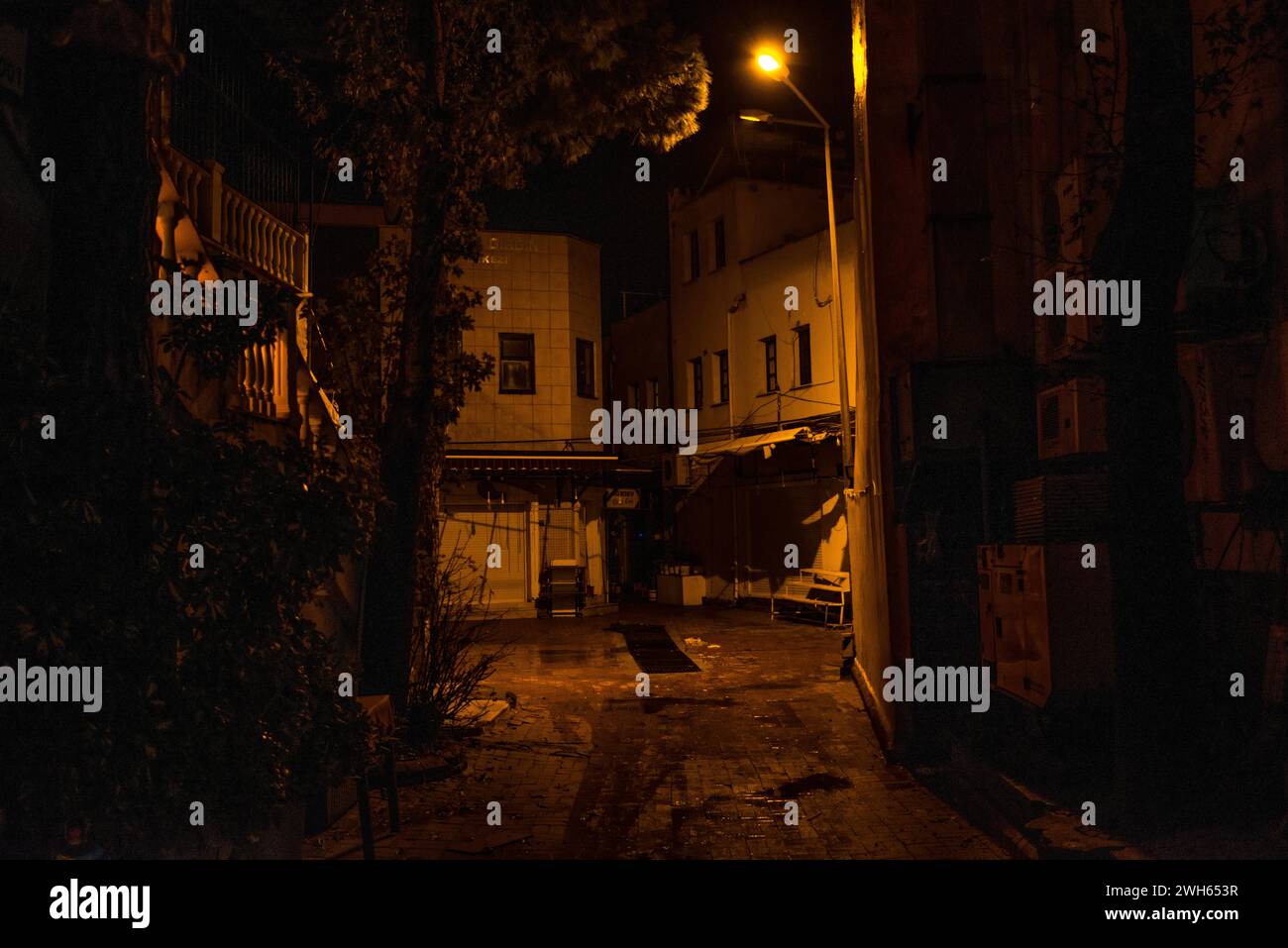 Une vue d'ambiance et d'humeur sombre d'une rue sombre la nuit après la pluie, avec des lumières de la ville brillantes et des reflets humides créant une ambiance urbaine. Banque D'Images