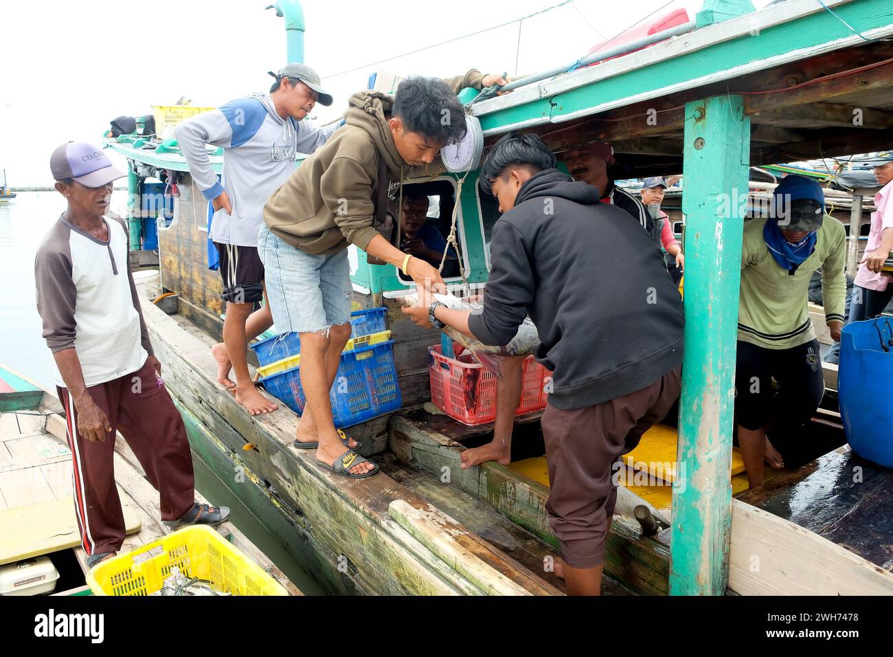 Lampung, Indonésie, 07 octobre 2022 : deux hommes indonésiens pèsent des poissons sur un bateau de pêche à Lampung, Indonésie. Banque D'Images