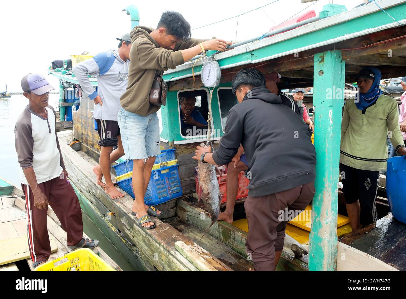 Lampung, Indonésie, 07 octobre 2022 : deux hommes indonésiens pèsent des poissons sur un bateau de pêche à Lampung, Indonésie. Banque D'Images