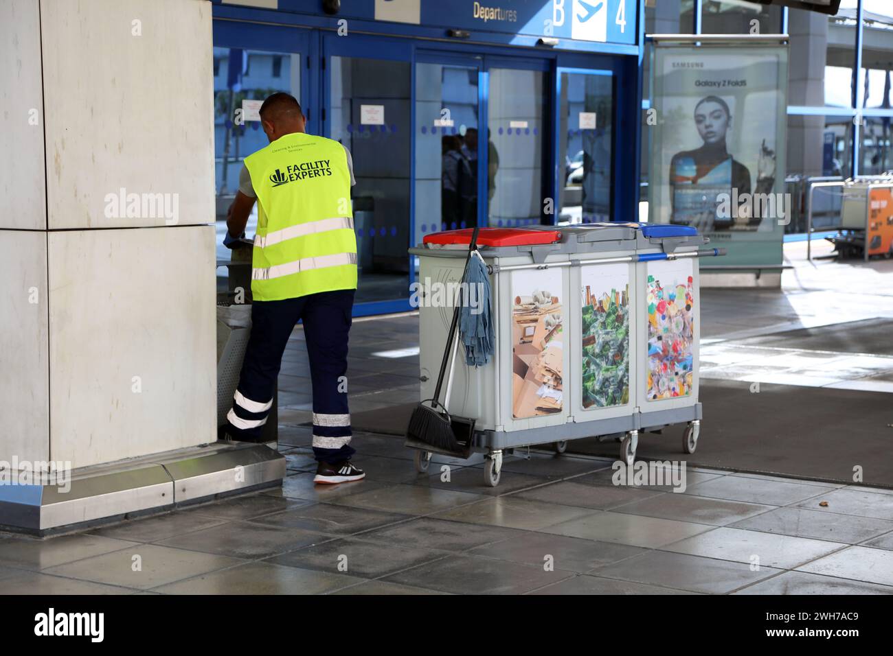Athènes Grèce Aéroport international d'Athènes (AIA) Eleftherios Venizelos employé de l'installation portant un gilet haute visibilité vidant les poubelles Banque D'Images