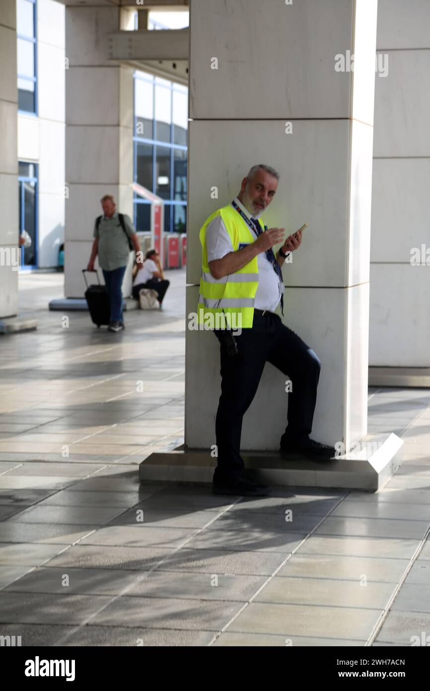 Athènes Grèce Aéroport International d'Athènes (AIA) Eleftherios Venizelos homme portant le gilet haute visibilité en utilisant le téléphone portable Banque D'Images