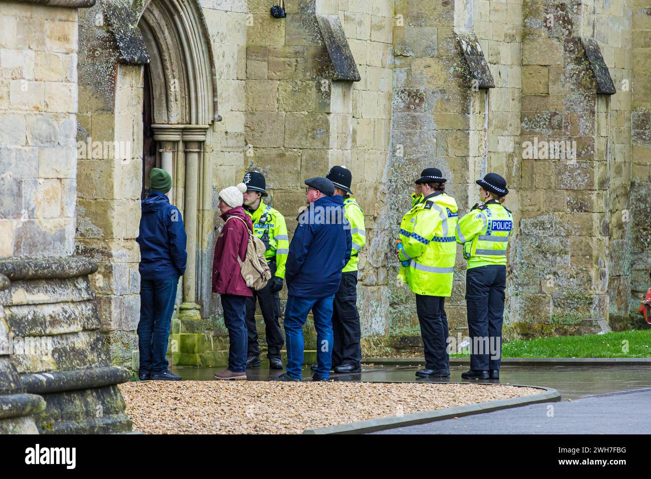 Des policiers vêtus de vestes jaunes interagissant avec des membres du public pendant une patrouille de sécurité à la cathédrale de Salisbury, Banque D'Images