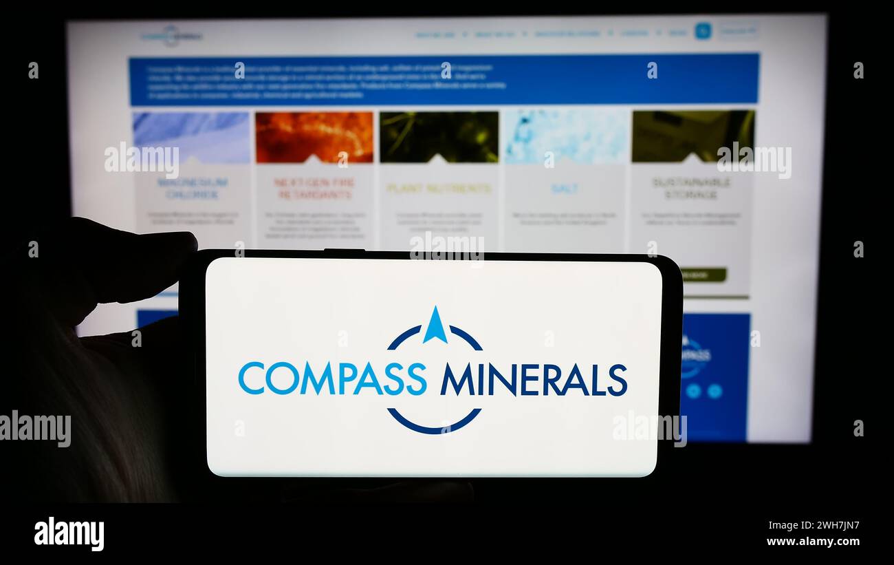 Personne tenant un smartphone avec le logo de la société minière américaine Compass Minerals International Inc en face du site Web. Concentrez-vous sur l'affichage du téléphone. Banque D'Images