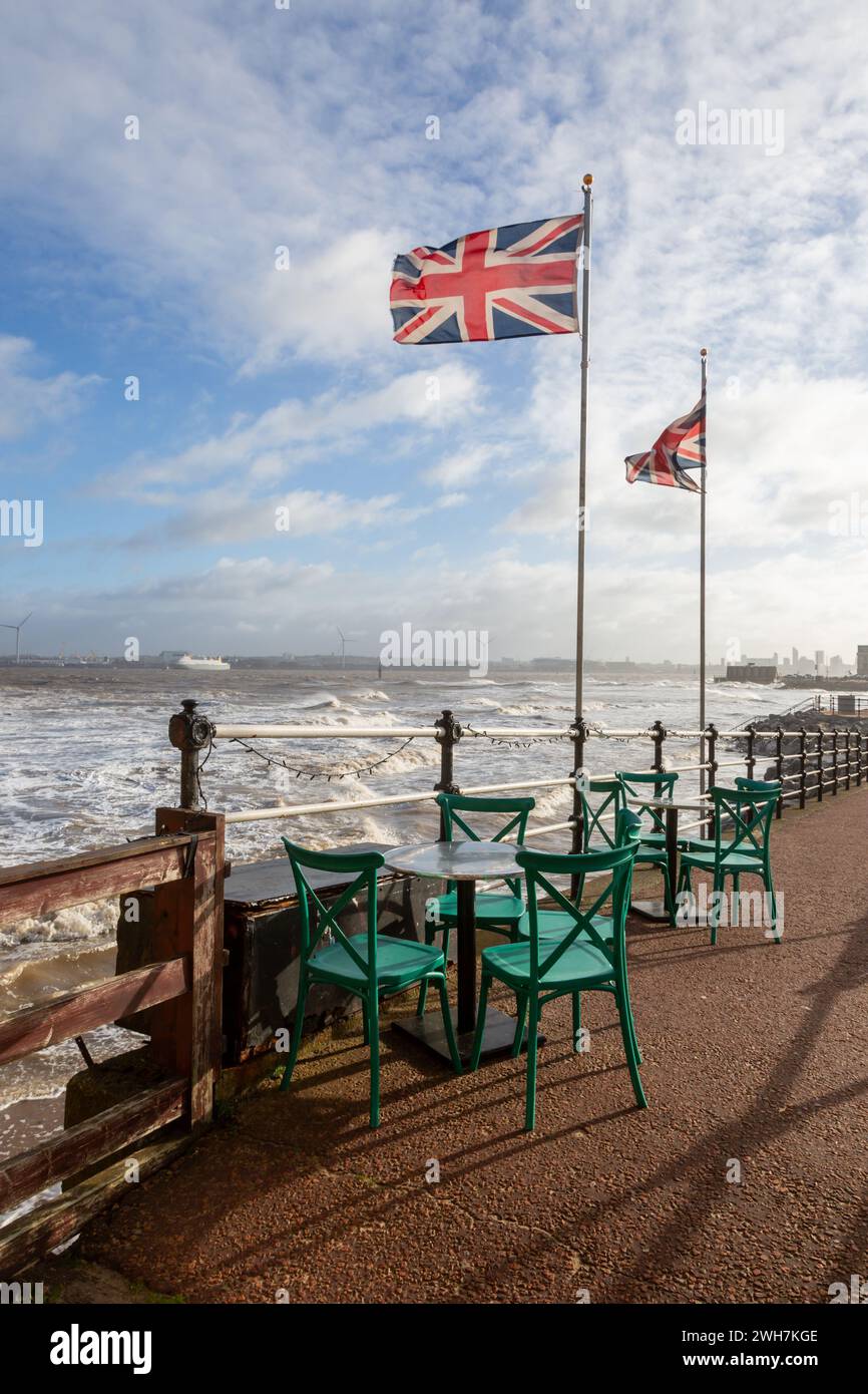 Sièges de café et tables par temps venteux avec drapeaux union jack, New Brighton, Wirral, Royaume-Uni Banque D'Images