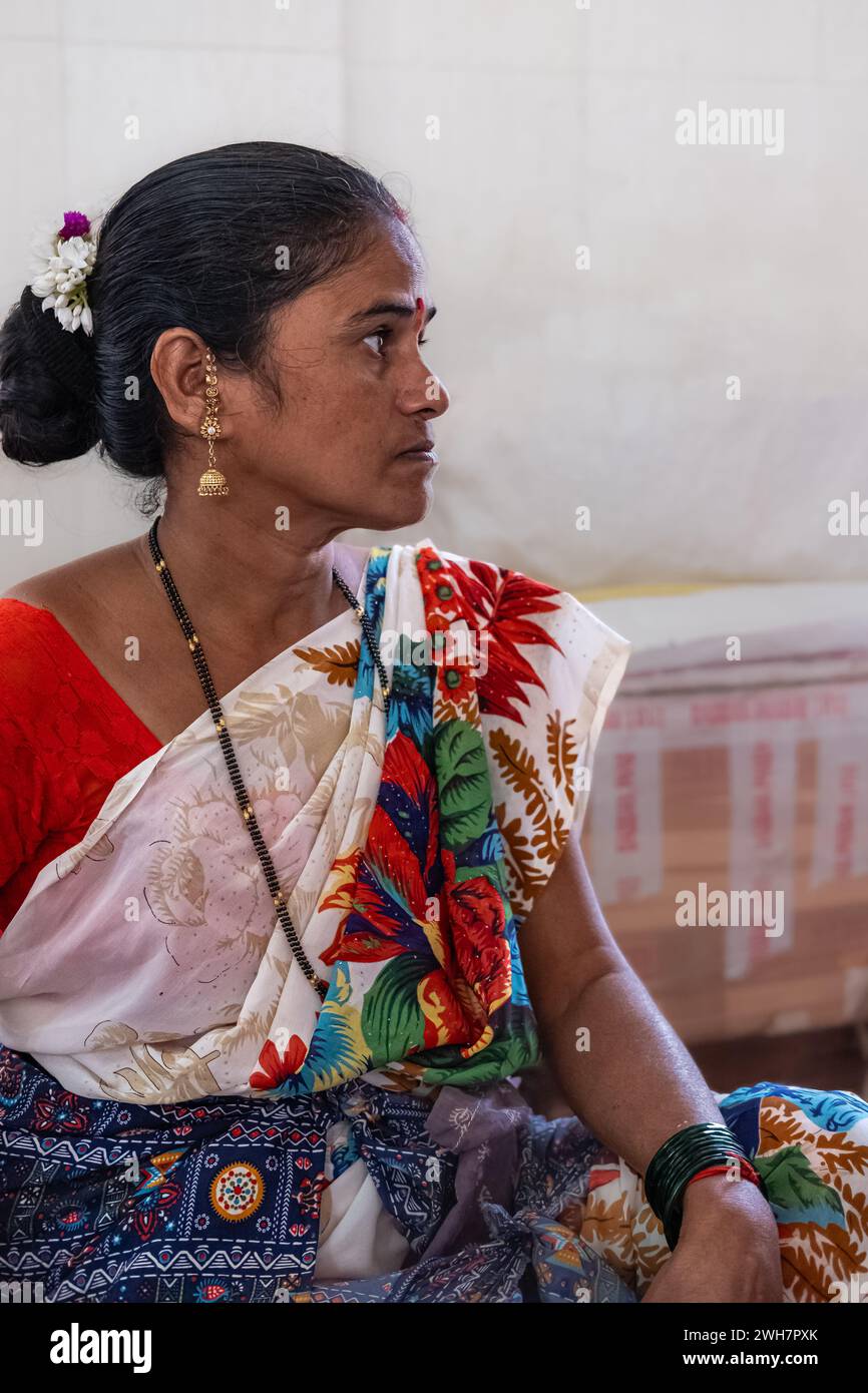 Portrait d'une jeune femme en vêtements traditionnels indiens assis dans une rue Goa Inde. Femme indienne d'âge moyen portant le saree. Photo de rue, éditorial Banque D'Images