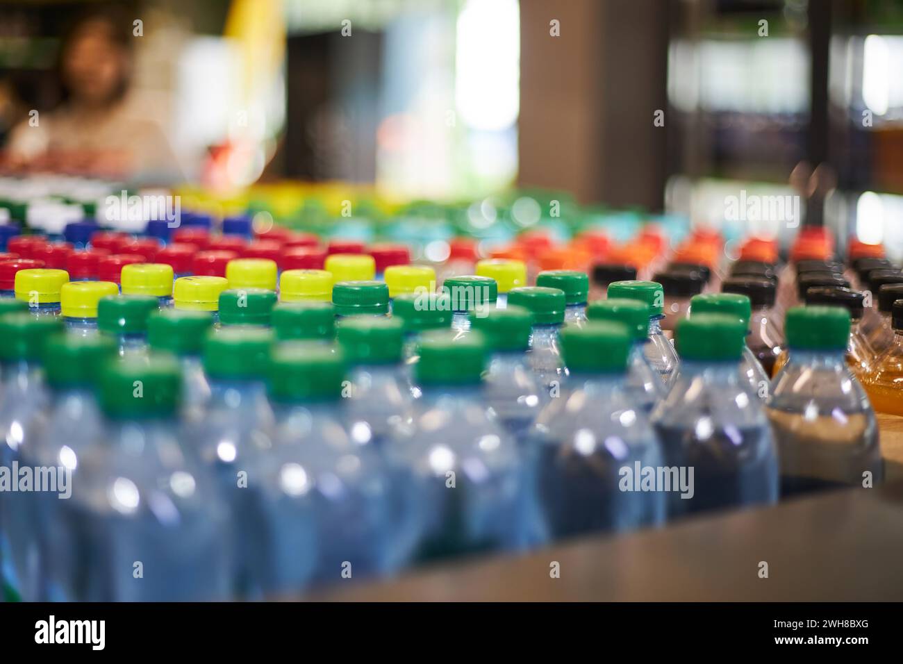 Lot de bouteilles d'eau minérale de petit volume en plastique bleu d'un demi-litre, bouchon rouge jaune vert dans le magasin, étagère de supermarché, gros plan. plasti haute consommation Banque D'Images