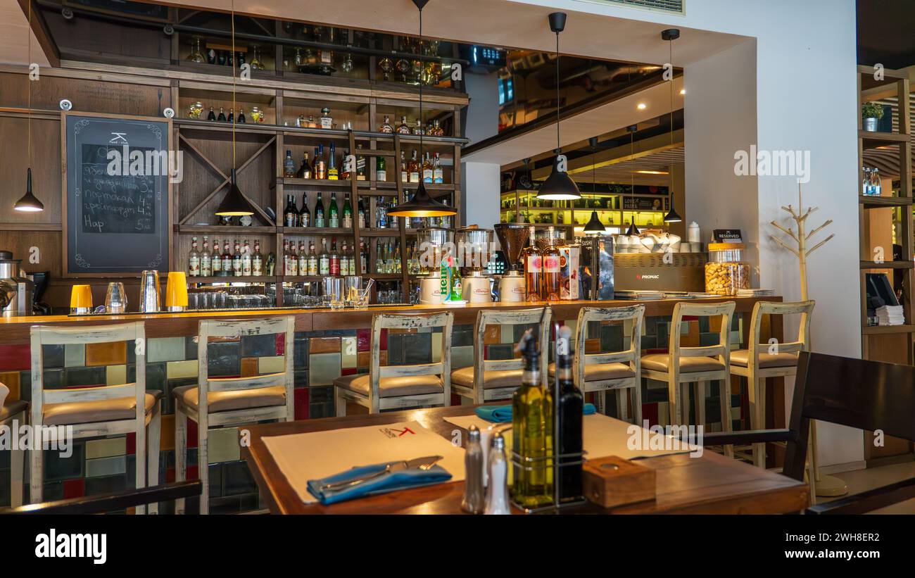 Un restaurant élégant orné de bouteilles de vin et doté de tables en bois rustiques accompagnées d'élégantes chaises blanches Banque D'Images