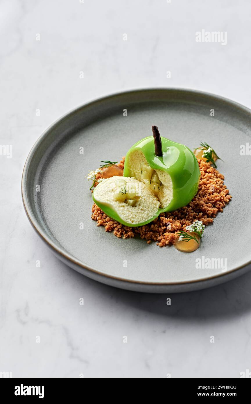Pomme verte fourrée de mousse de vanille et chocolat blanc, compote de pomme et d'aneth, et servie avec crumble d'avoine salé et gel de pomme Banque D'Images