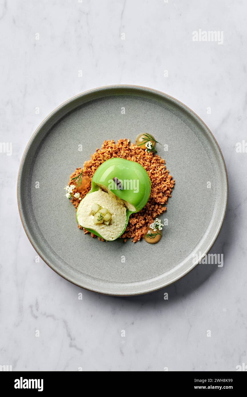 Pomme verte fourrée de mousse de vanille et chocolat blanc, compote de pomme et d'aneth, et servie avec crumble d'avoine salé et gel de pomme Banque D'Images