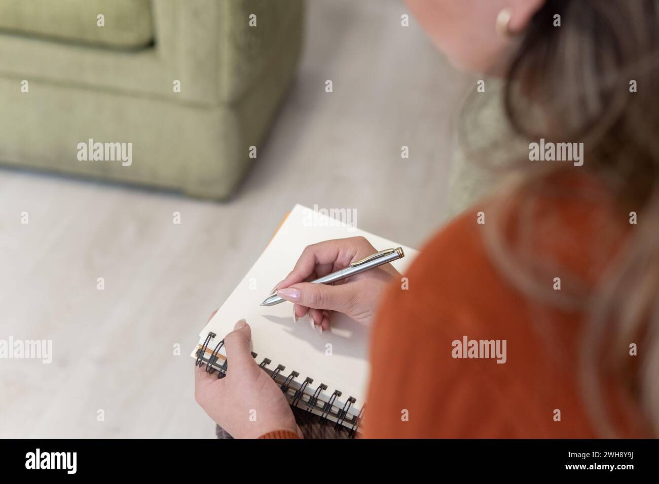 gros plan de la main d'une femme depuis son dos prenant des notes dans un cahier avec un stylo Banque D'Images