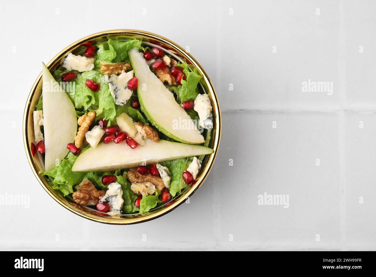 Délicieuse salade de poires dans un bol sur une table carrelée légère, vue de dessus. Espace pour le texte Banque D'Images