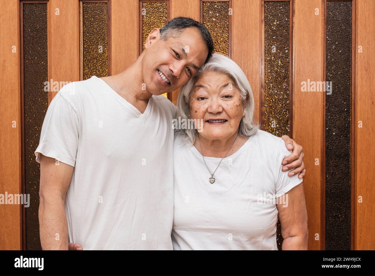 Heureuse mère asiatique plus âgée et fils adultes serrés affectueusement, regardant la caméra, souriant, profitant de la visite de la famille, temps libre. Banque D'Images
