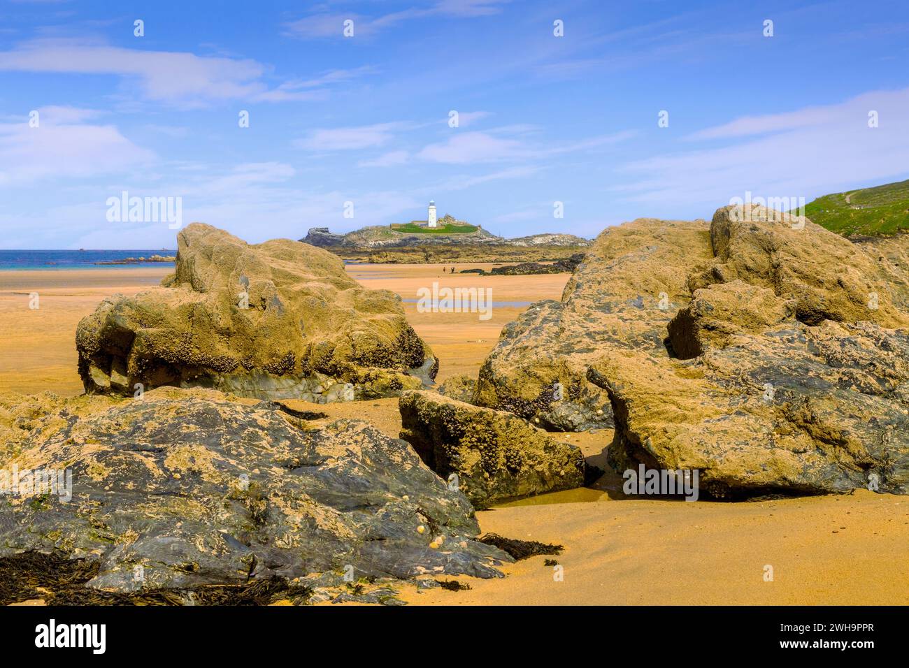 Phare de Godrevy et d'énormes rochers révélés sur la plage à marée basse lors d'une journée de printemps parfaite. Banque D'Images