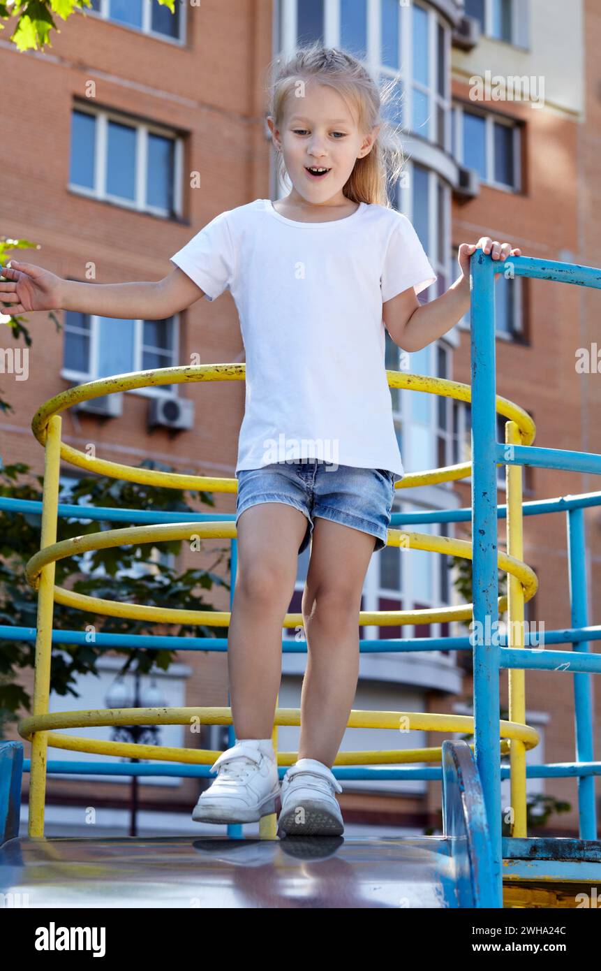 Petite fille jouant sur un toboggan dans une aire de jeux dans le parc de la ville d'été. Enfance, loisirs et concept de personnes - repos heureux de l'enfant et passer un bon moment Banque D'Images