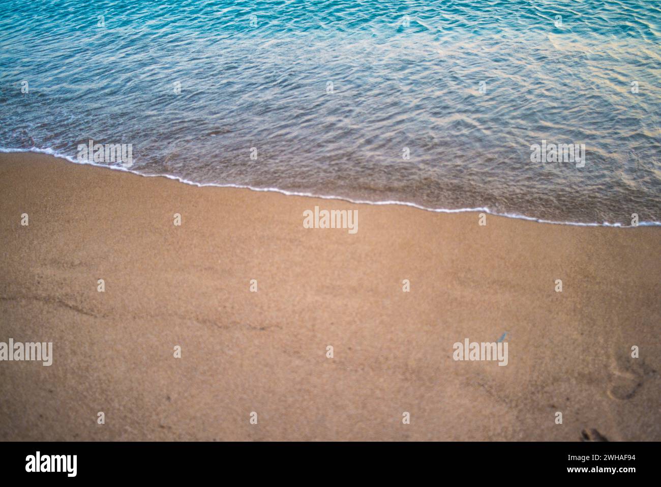 Une scène tranquille comme les gens profitent d'un coucher de soleil nager dans la mer calme, baigné dans les teintes chaudes du crépuscule, créant une atmosphère côtière sereine. Banque D'Images