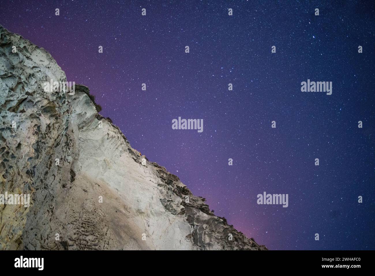 Une scène côtière à couper le souffle où la voie Lactée orne le ciel nocturne sur la mer et la montagne, créant une merveille sereine et cosmique. Banque D'Images