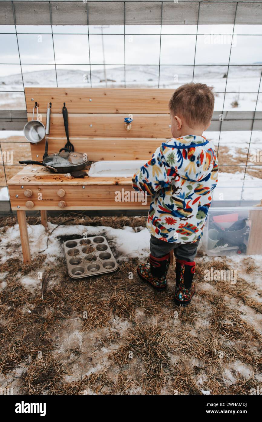 Petit garçon aime jouer enneigé avec la cuisine de boue Banque D'Images