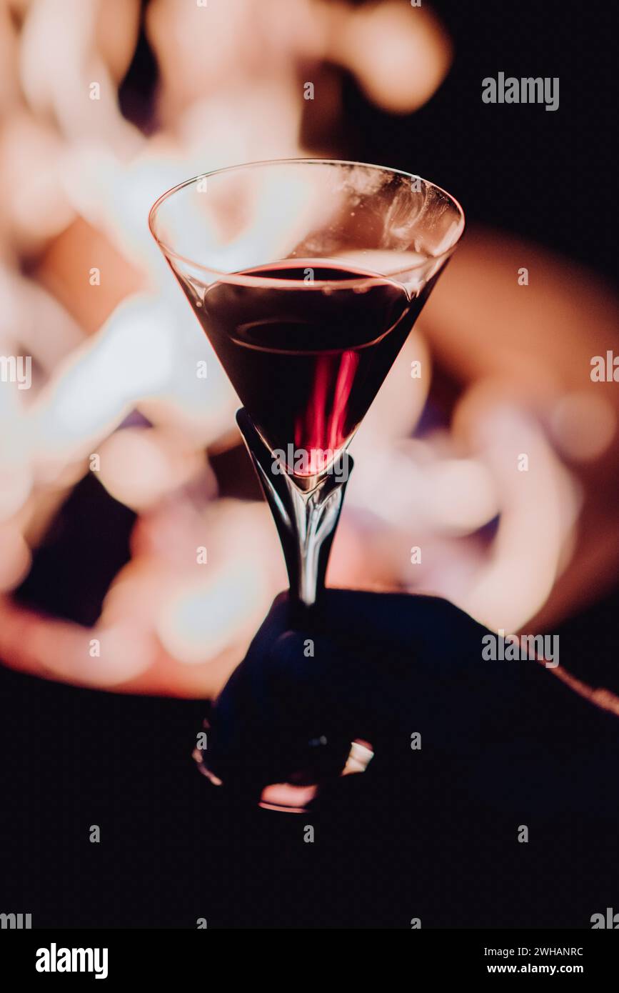 Main tenant un verre de vin rouge avec un feu chaud en arrière-plan Banque D'Images