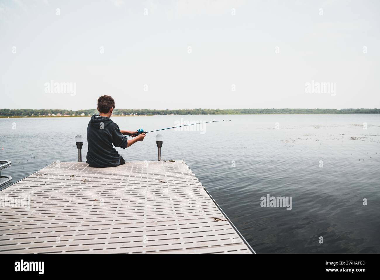 Le jeune garçon va pêcher au large D'Un quai Banque D'Images