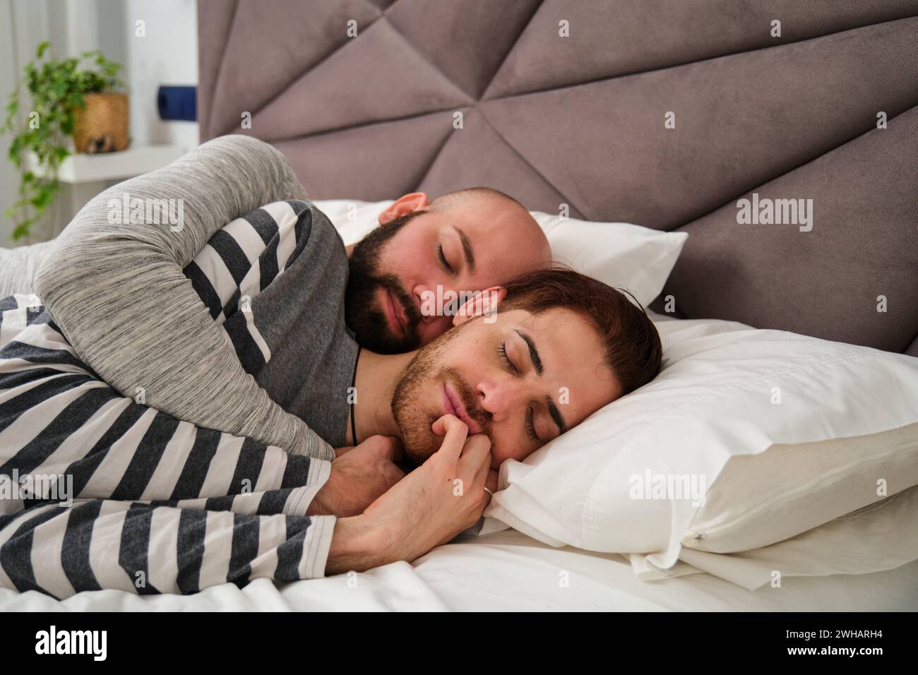 Couple homosexuel dormant dans ses bras au lit. Banque D'Images