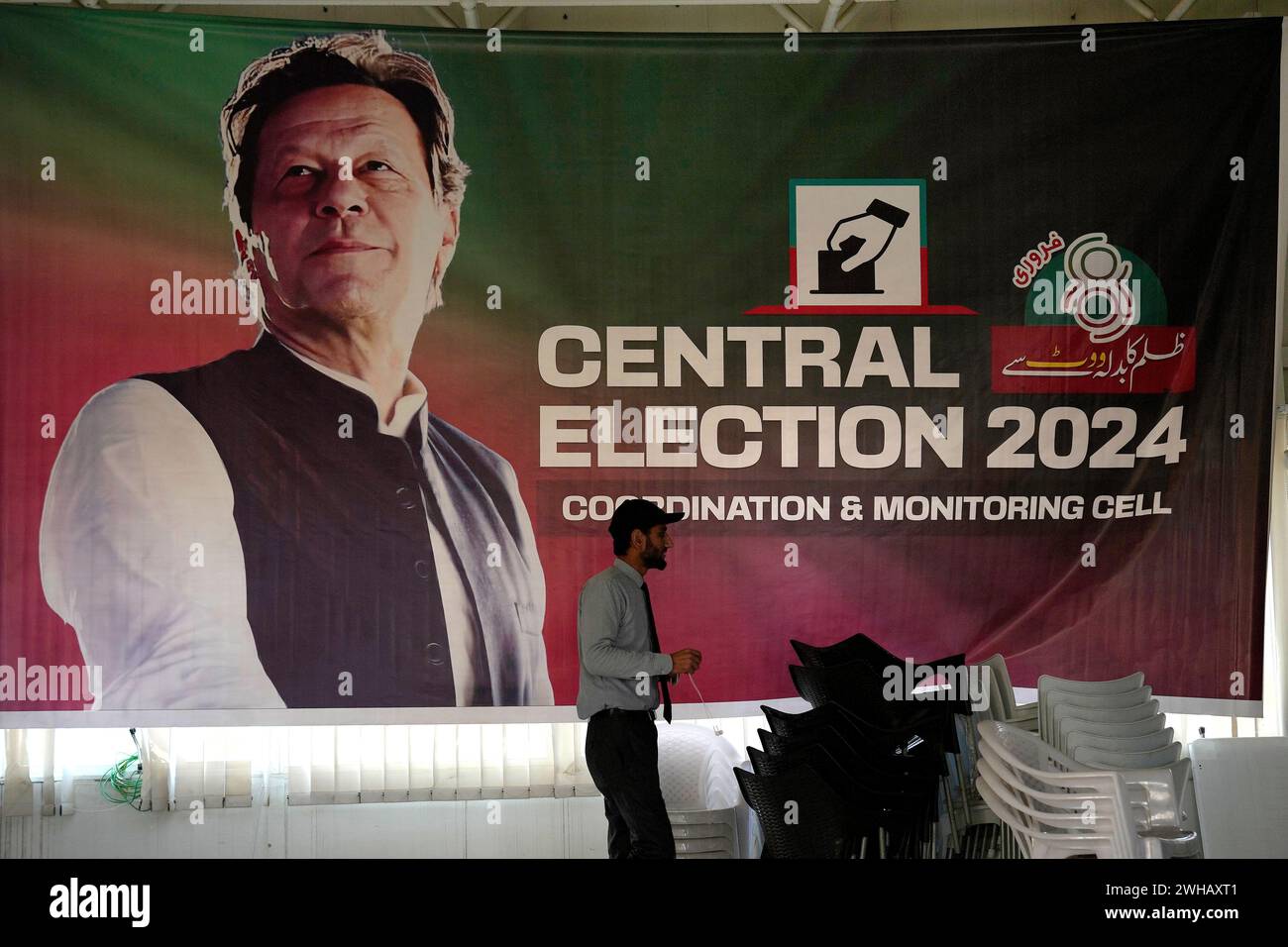 A supporter walks past a poster of imprisoned leader Pakistan's Former Prime Minister Imran Khan display at his party office, in Islamabad, Pakistan, Friday, Feb. 9, 20204. Independent candidates backed by Khan's party were leading Pakistan's national election results, a day after sporadic violence, allegations of a preordained outcome and a cell phone service shutdown overshadowed the vote. (AP Photo/Anjum Naveed) Banque D'Images