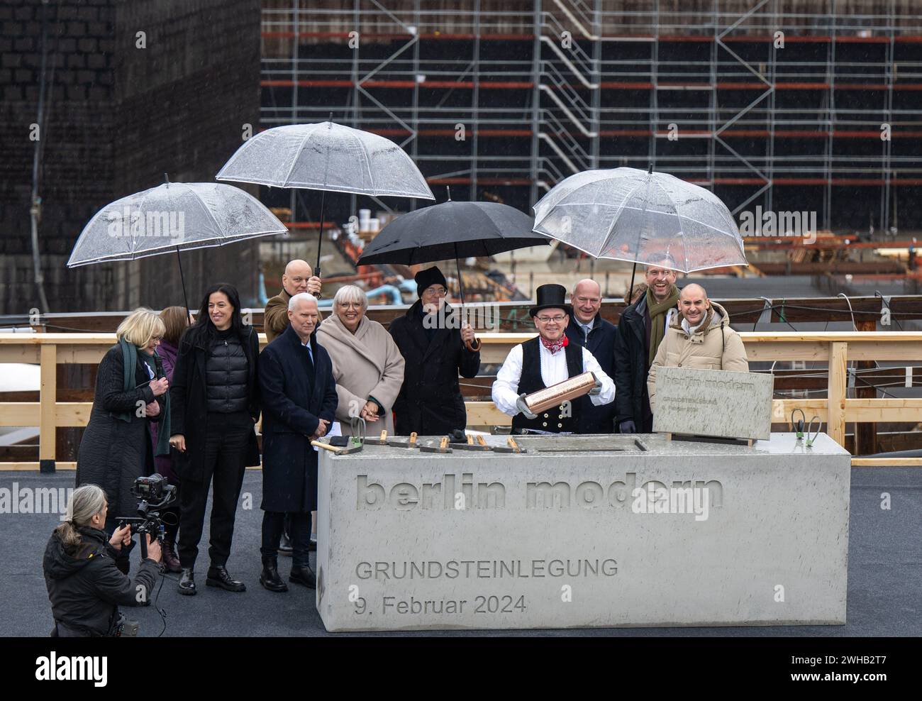 09 février 2024, Berlin : Klaus Biesenbach (devant, 3e à gauche), directeur de la Neue Nationalgalerie, Claudia Roth (devant, 4e à gauche, Bündnis 90/Die Grünen), ministre d’État à la culture et aux médias, Jacques Herzog (5e à gauche), architecte, Kai Wegner (deuxième rangée, 3e à droite, CDU), maire de Berlin, et d'autres participants au projet se tiennent sur le site de construction du musée lors d'une séance photo pour marquer la pose de la première pierre du nouveau musée moderne de berlin. La Maison de l'art du XXe siècle est en construction au Kulturforum selon les plans des architectes suisses Herz Banque D'Images