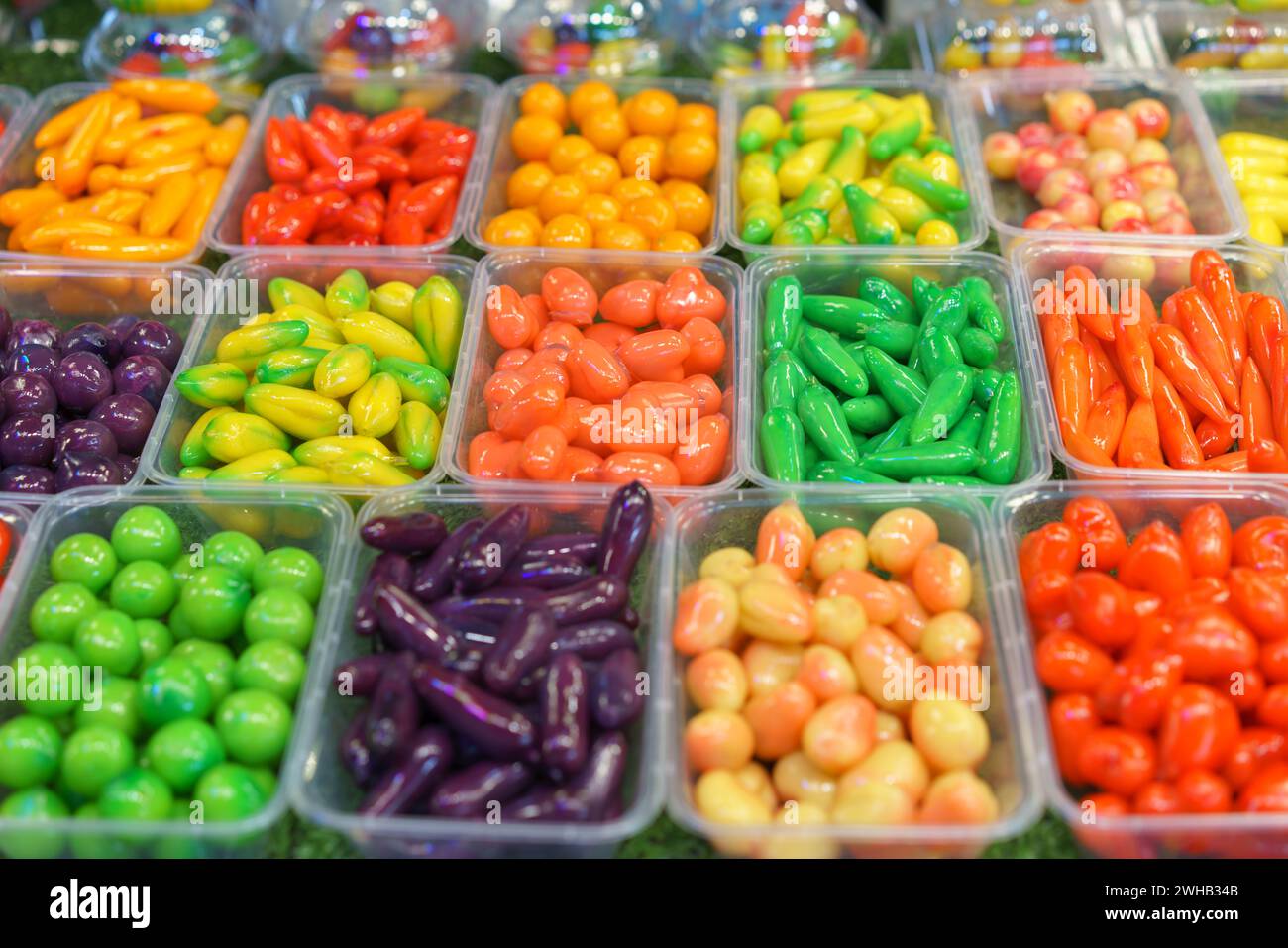 Un assortiment de haricots mung en forme de fruits, des desserts thaïlandais vibrants, conçus pour ressembler à des fruits et légumes miniatures, présentés dans des récipients transparents à Banque D'Images