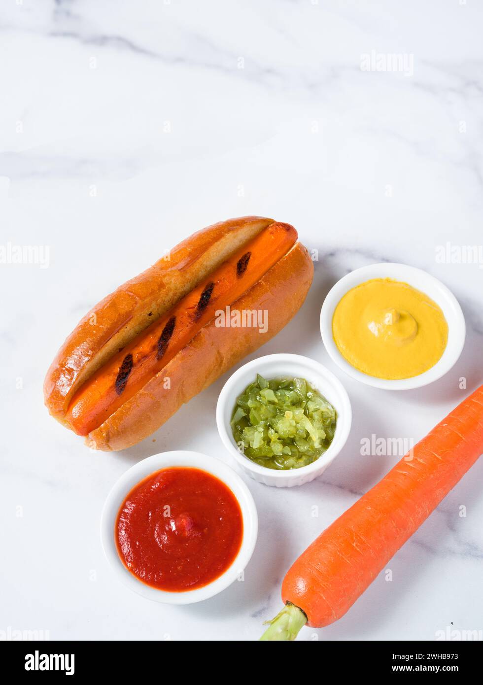 Alternative à la viande d'un chien carotte avec des condiments et une carotte crue sur une surface en marbre ; concept alimentaire à base de plantes avec espace de copie Banque D'Images