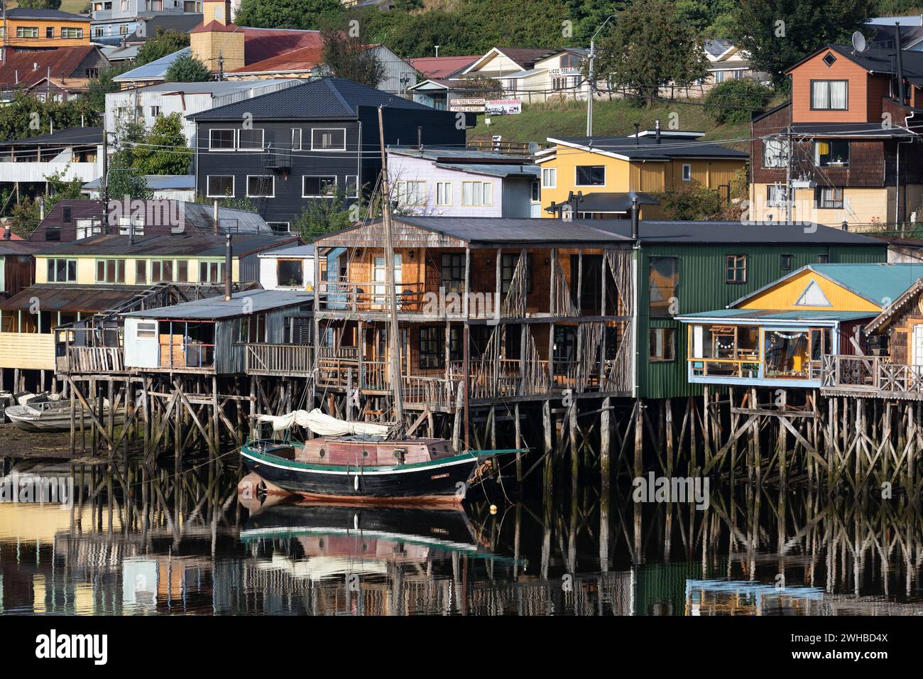 Un voilier devant les maisons colorées sur pilotis, les soi-disant palafitos, de la capitale Castro sur l'île de Chiloé au Chili. Banque D'Images