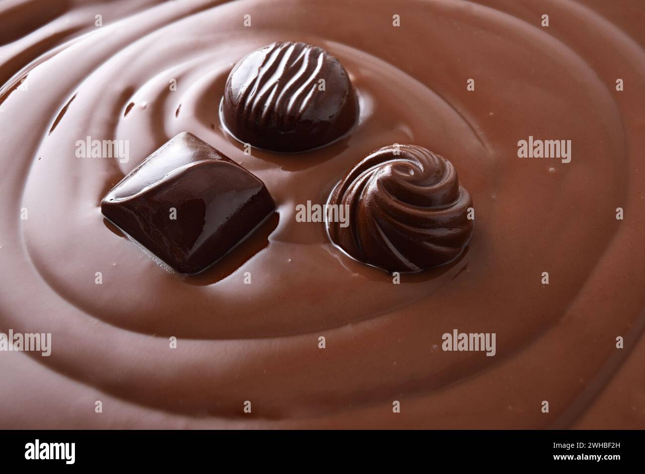 Trois bonbons au chocolat noir différents trempés dans de la crème au chocolat. Vue surélevée. Banque D'Images