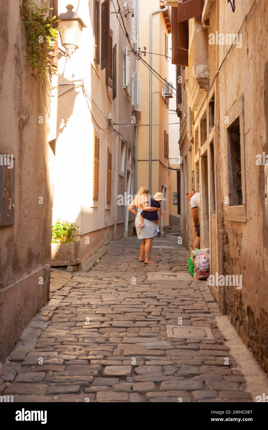 Piran, Slovénie - 26 août 2023 : maman avec un enfant dans les bras le long des ruelles de Pirano Banque D'Images