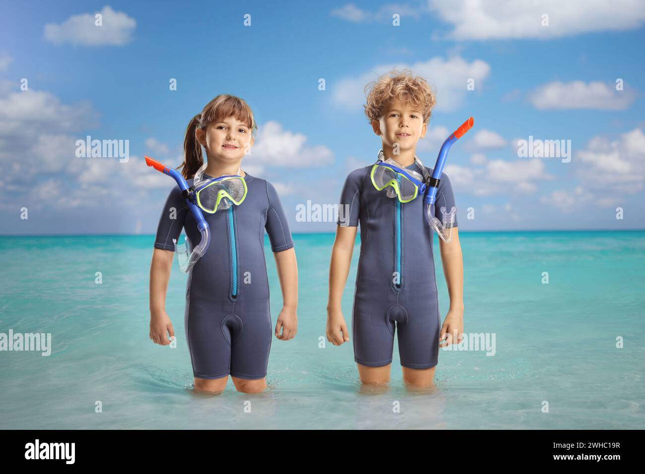 Fille et garçon en combinaisons et masques de plongée debout dans la mer Banque D'Images