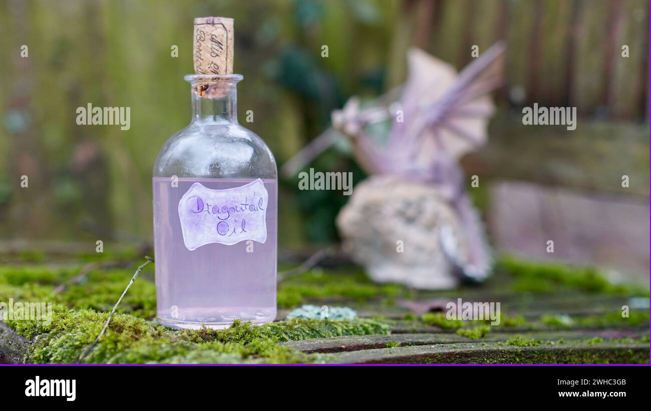 Une bouteille en verre avec de l'huile de queue de dragon omg Moss- Un petit dragon. Banque D'Images