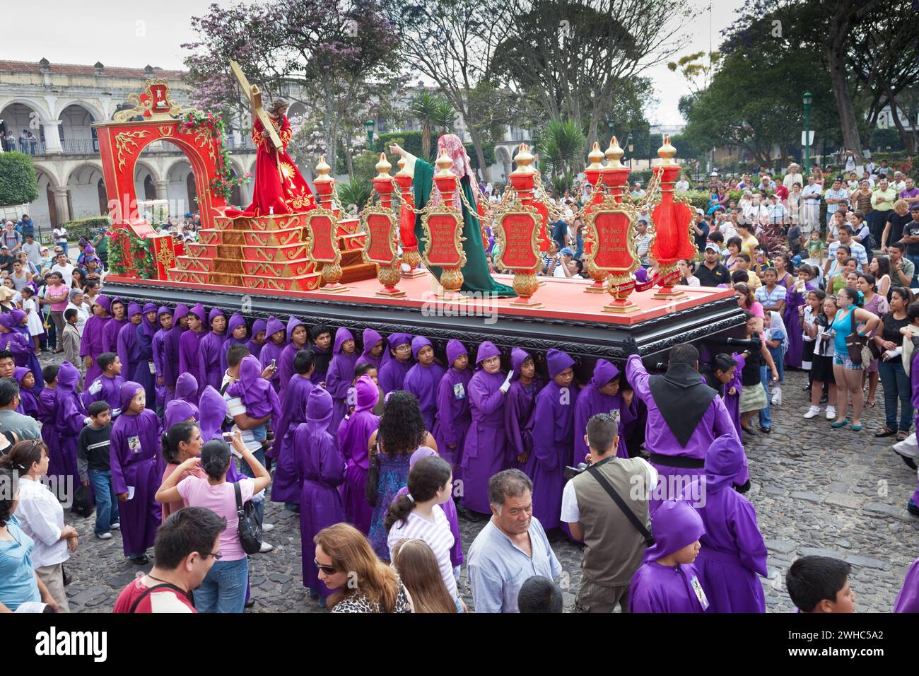 Antigua, Guatemala. Spectateurs, famille et touristes observez des adolescents portant un flotteur dans une procession religieuse pendant la semaine Sainte, la Semana San Banque D'Images