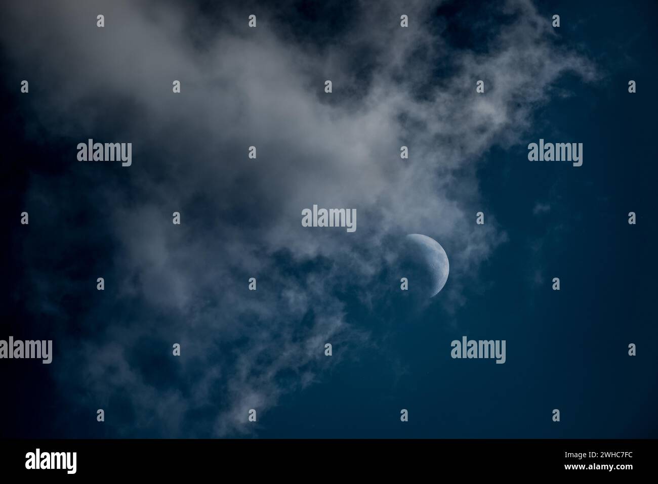 Le croissant de la lune cirée dans le deuxième quartier brille dans un ciel bleu foncé, nuageux, comme un conte de fées, tir de nuit mystique, sombre, un peu effrayant Banque D'Images