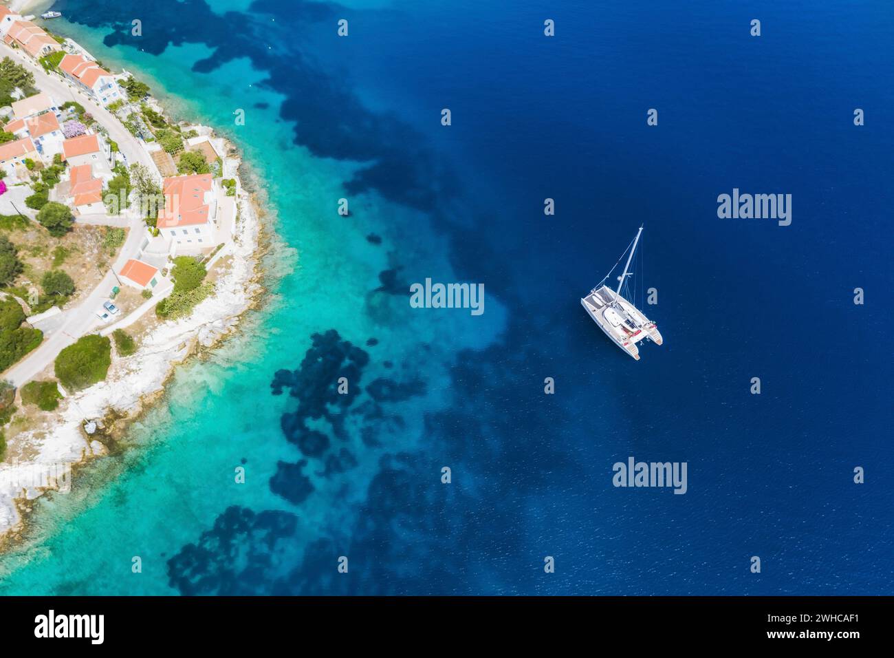 Bateau à voile yacht dans la mer bleue arrivent Fiscardo village dans l'île de Kefalonia, Grèce. Banque D'Images