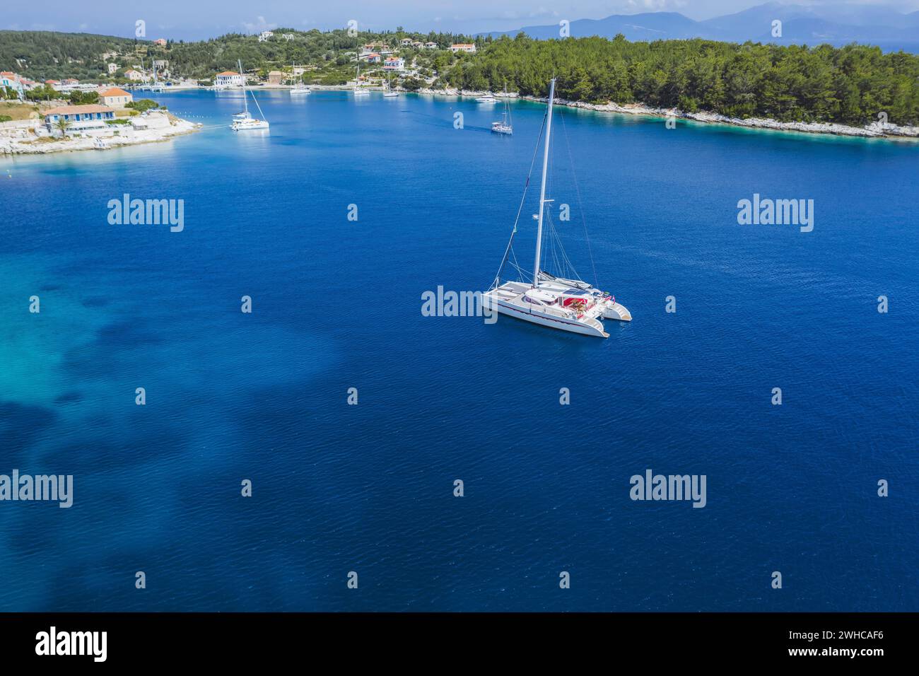 Bateau à voile yacht dans la mer bleue arrivent Fiscardo village dans l'île de Kefalonia, Grèce. Banque D'Images