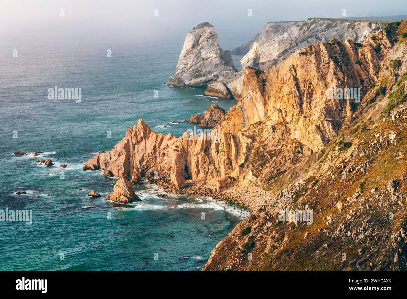 Sintra, Portugal. Côte rocheuse entre le cap Roca et Praia da Ursa dans la lumière du coucher du soleil et l'océan Atlantique. Banque D'Images