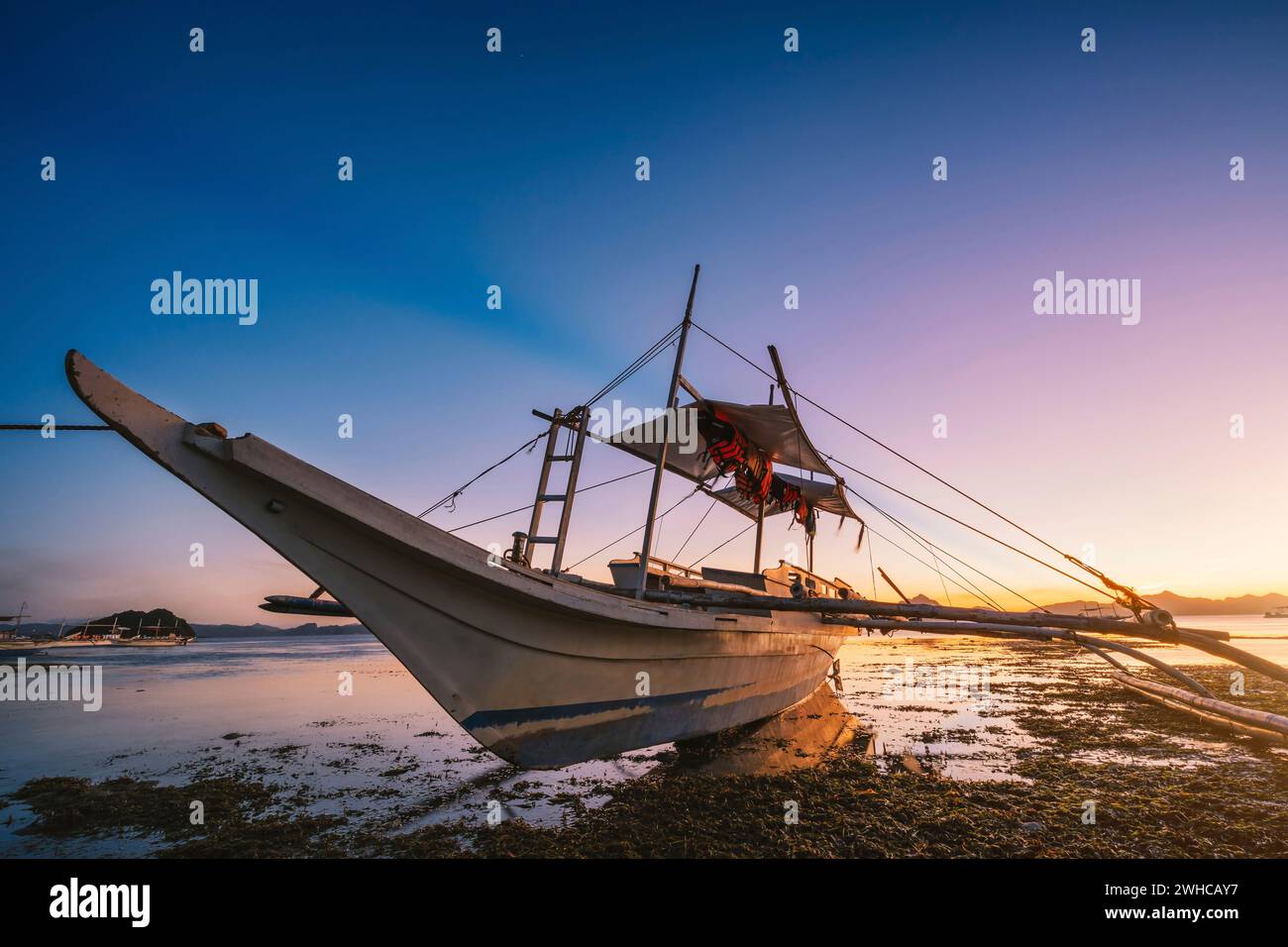 El Nido, île de Palawan, Philippines. Bateau dans la lumière douce luisante du coucher du soleil sur la plage tropicale. Banque D'Images