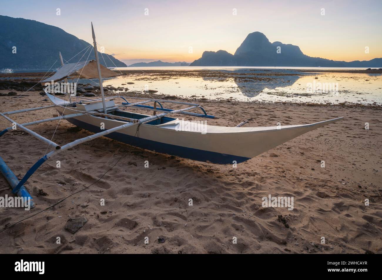 Coucher de soleil tropical coloré avec un bateau banca local à El Nido, Palawan - Philippines. Banque D'Images