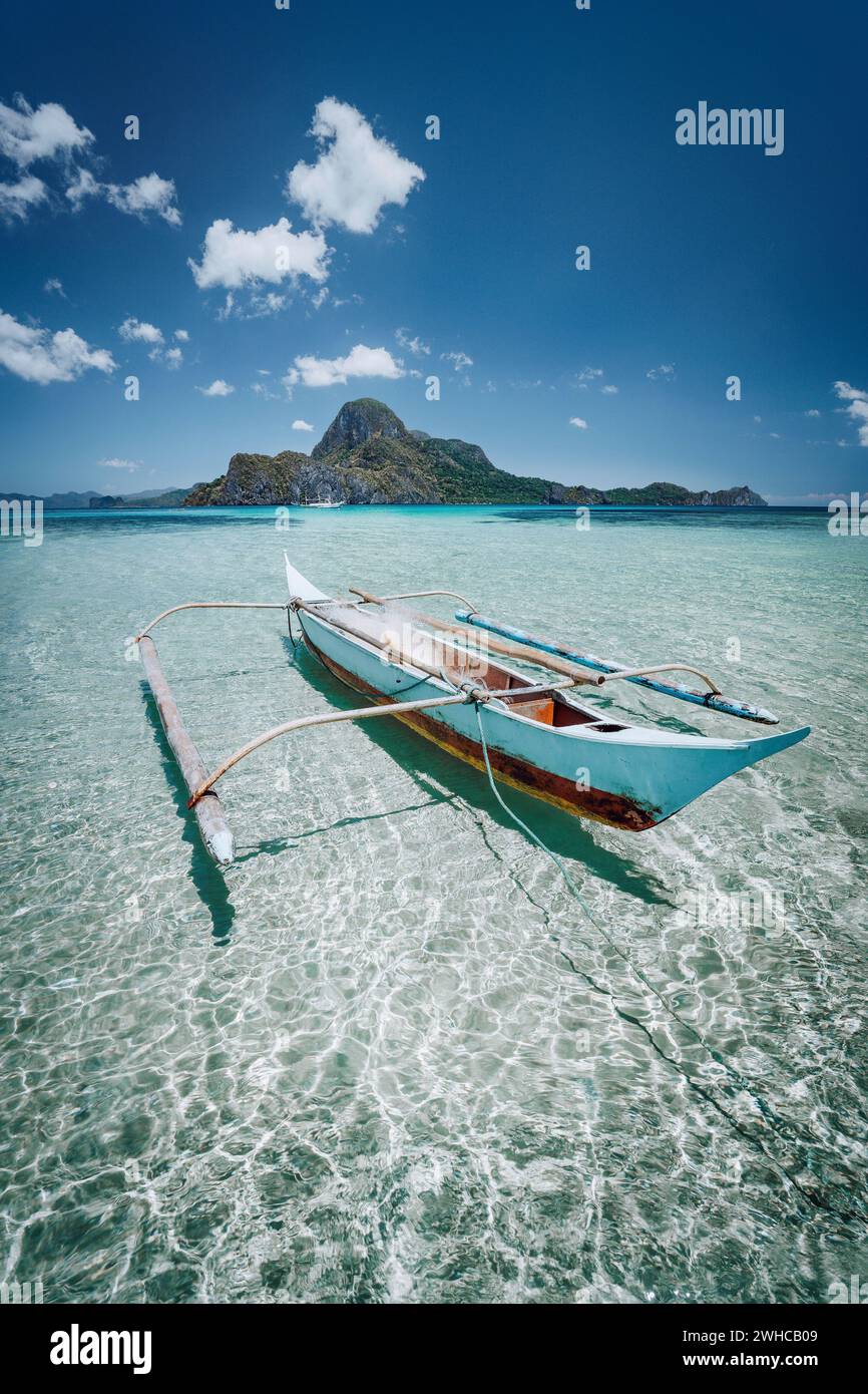 Petit bateau de pêche banca en face de l'Île Cadlao dans des eaux peu profondes, à marée basse, une nature de Palawan, Philippines. Banque D'Images