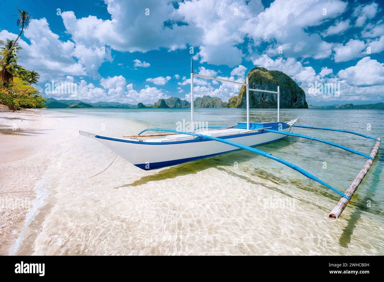 El Nido, Palawan, Philippines. Paysages tropicaux de banca bateau sur la plage de sable fin prêt pour tour d'île en île. L'île de Pinagbuyutan en arrière-plan. Banque D'Images