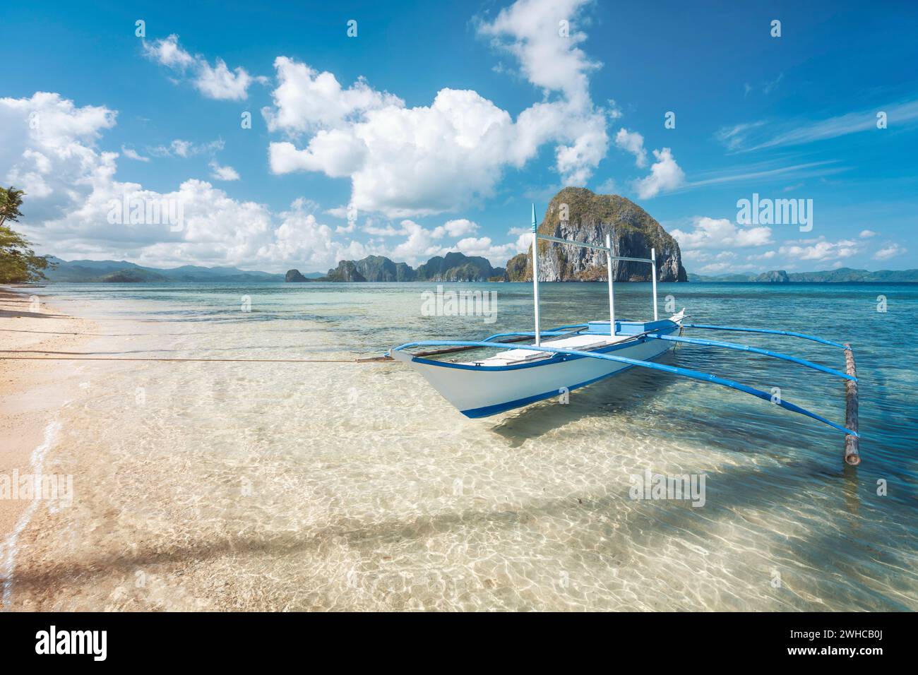 El Nido, Palawan, Philippines. Bateau banca traditionnel sur une plage de sable avec des eaux cristallines le matin, excursion sur l'île. Incroyable île de Pinagbuyutan en arrière-plan. Paysage magnifique. Banque D'Images