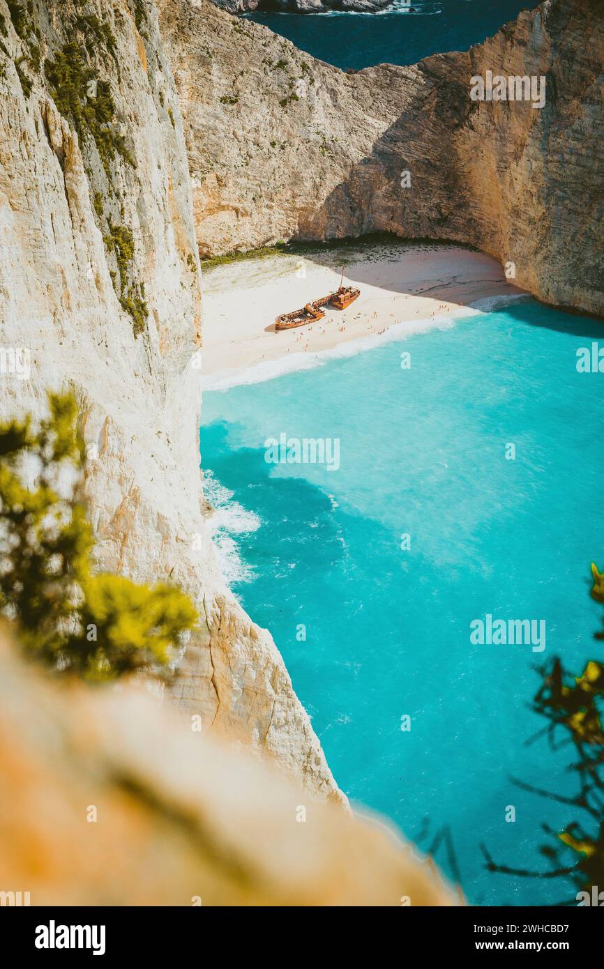 Plan vertical du naufrage sur la plage de Navagio avec de l'eau de mer bleu turquoise entourée d'énormes falaises blanches. Emplacement célèbre de point de repère sur l'île de Zakynthos, Grèce. Couleurs chaudes Banque D'Images