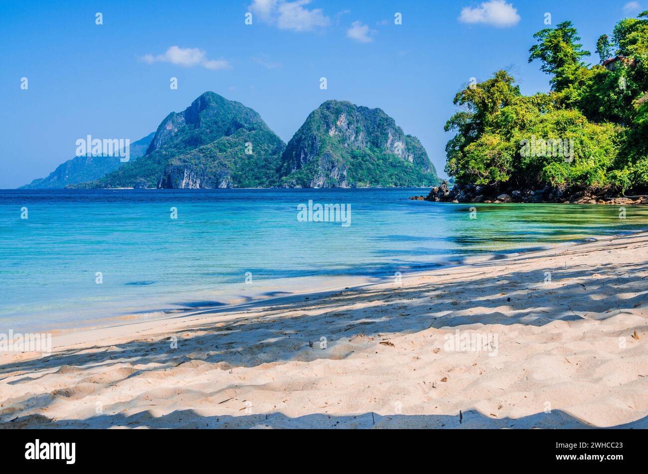 Plage de sable avec Palm Shadows, d'énormes rochers en arrière-plan, El Nido, Palawan, Philippines. Banque D'Images