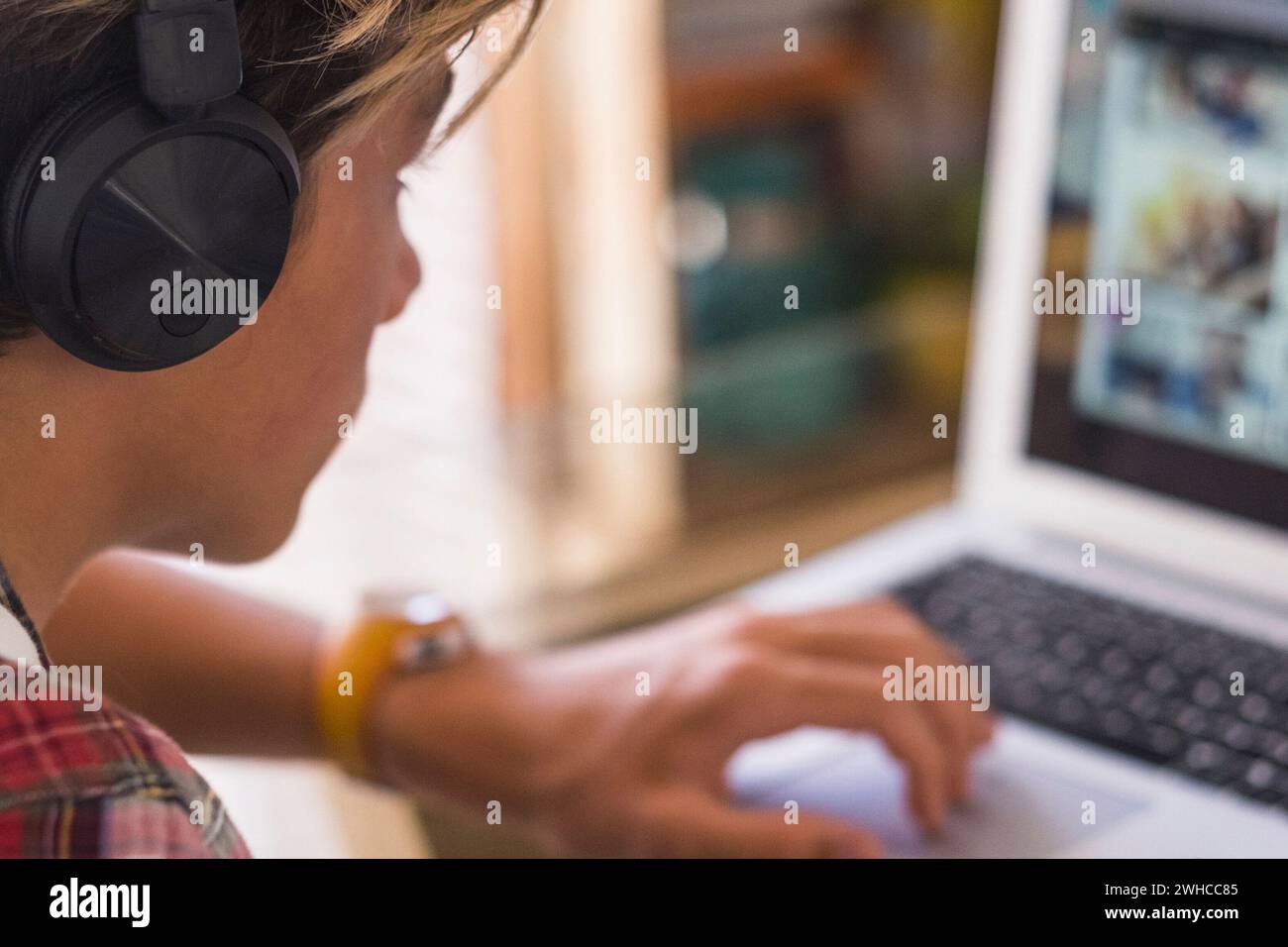 seul adolescent caucasien se concentrant pour ses devoirs avec son ordinateur portable - mec millénaire travaille à la maison - enfant d'intérieur jouant à des jeux vidéo Banque D'Images