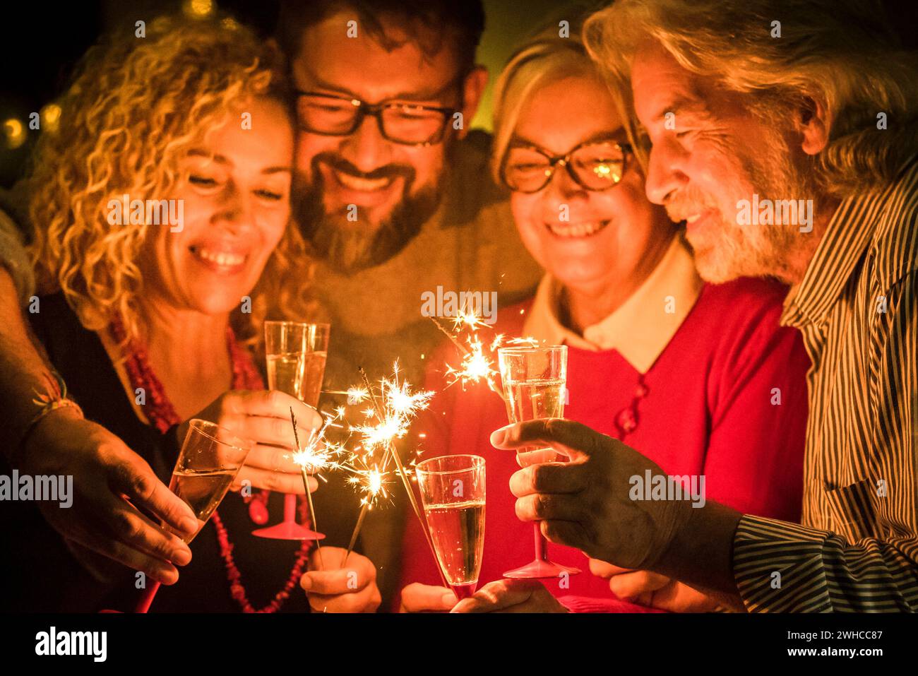 groupe de deux aînés et deux adultes qui s'amusent ensemble avec des joueurs de sparlers la nouvelle année à célébrer - famille heureuse avec lumières Banque D'Images