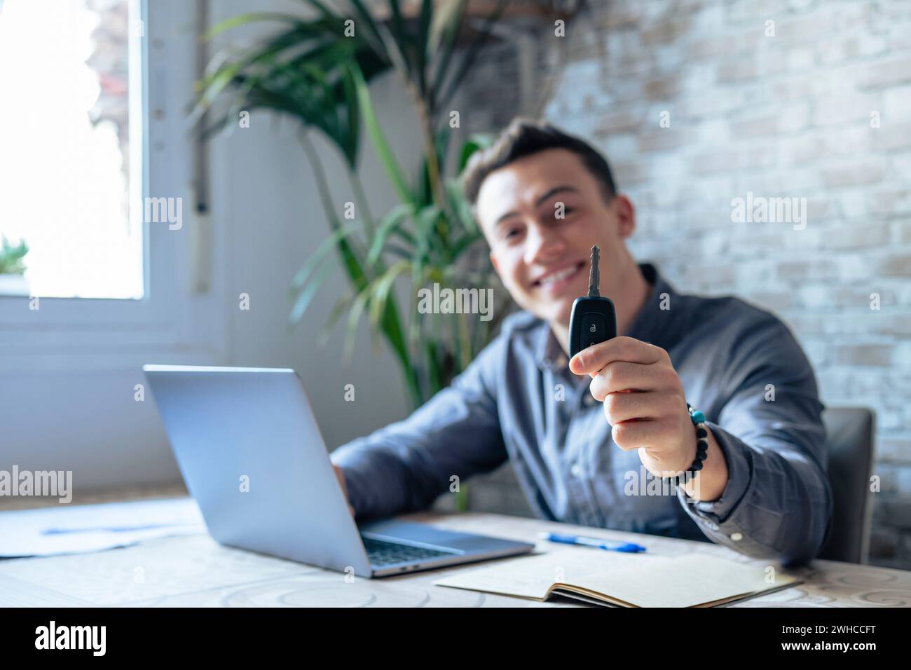 Portrait gros plan de la main d'un jeune homme beau et attrayant montrant et tenant les clés de la voiture à la caméra, emmenant au client achetant un nouveau véhicule. Vendeur travaillant sur les affaires Banque D'Images