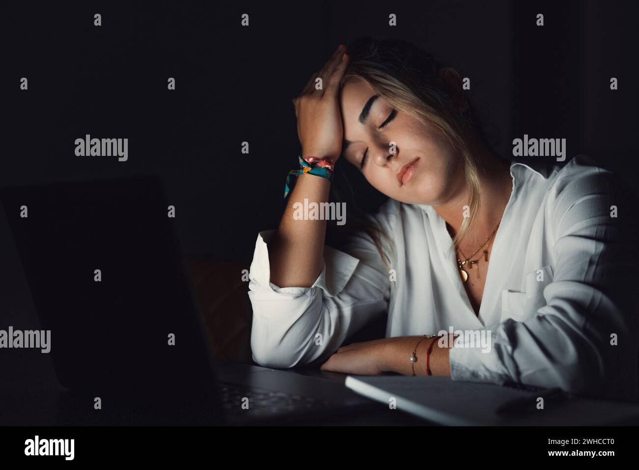 Jeune étudiant caucasien accablé touchant la tête, souffrant d'une vue floue, massant le pont de nez soulageant la douleur, se sentant épuisé travaillant tard dans la soirée sur l'ordinateur au bureau. Banque D'Images